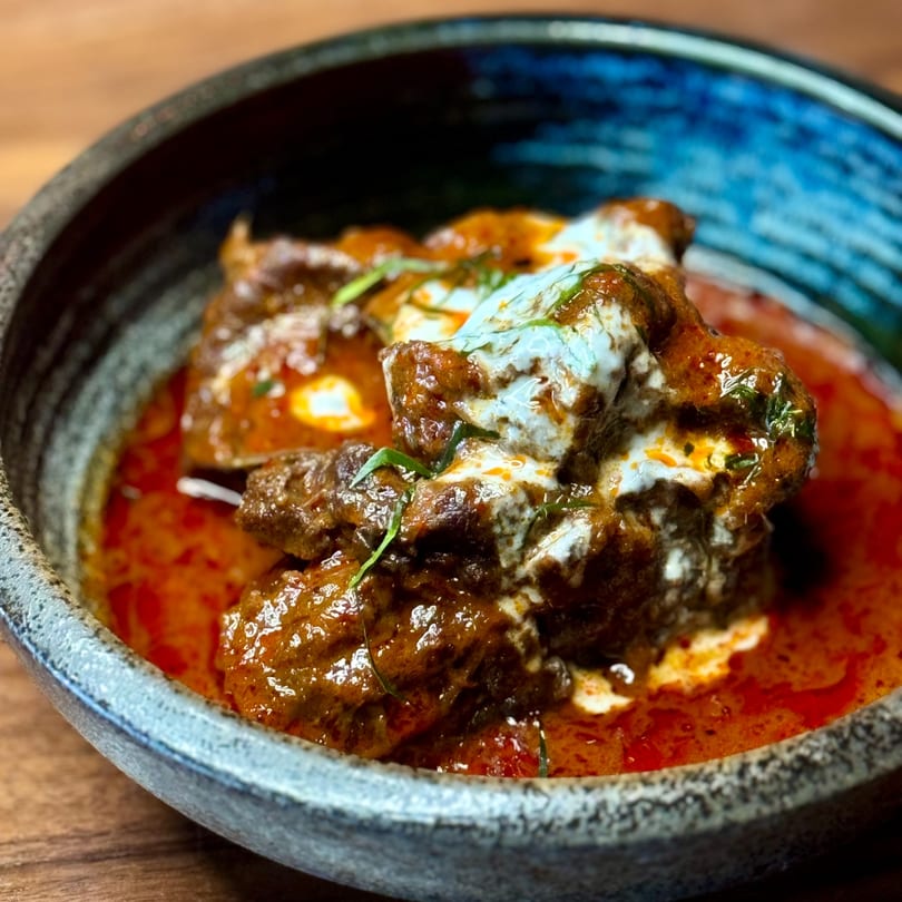 Close-up of Chao Krung Thai's Massaman Curry, with tender beef, rich red sauce, and coconut cream.